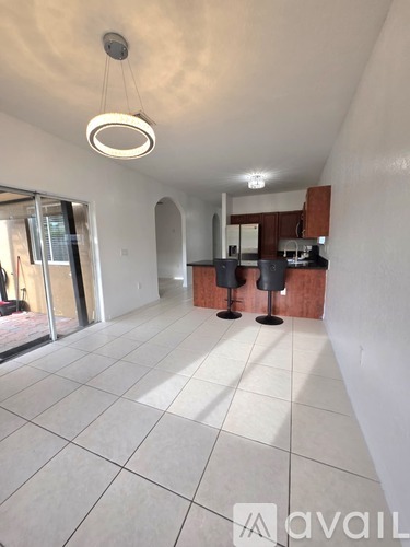 A spacious room with a kitchen area and a large mirror.