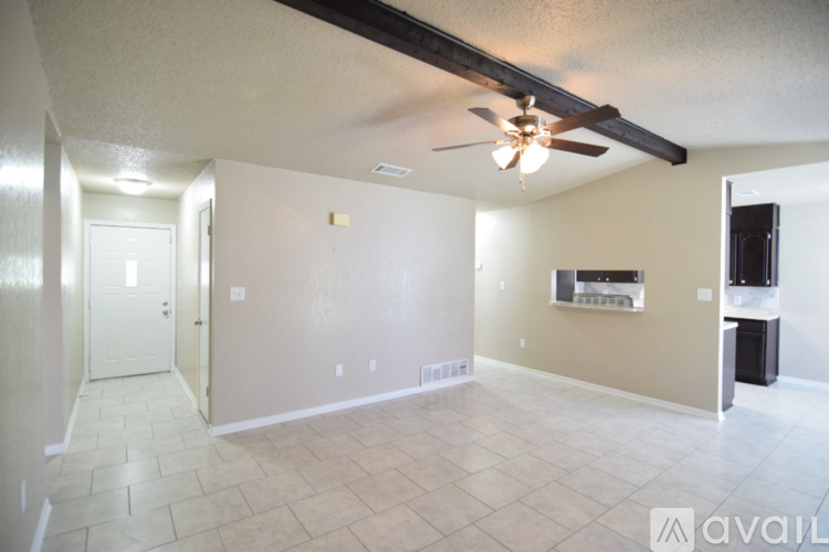 A spacious living room with a ceiling fan and a flat screen TV mounted on the wall.