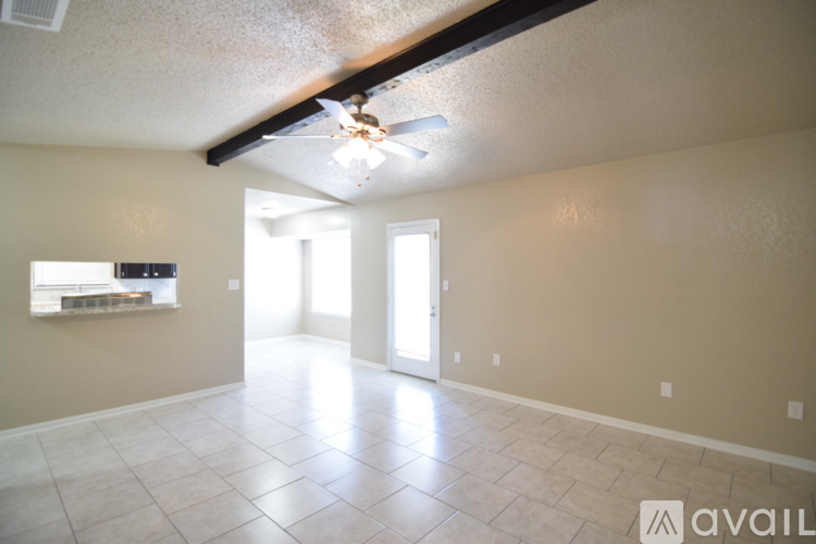 A spacious room with tile flooring and a ceiling fan.
