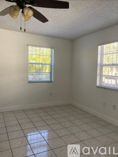A room with a ceiling fan and two windows.