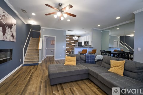 A living room with a grey sofa and a ceiling fan.
