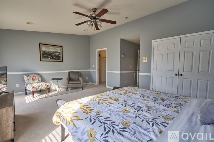 A bedroom with a bed in the center and a fan on the ceiling.