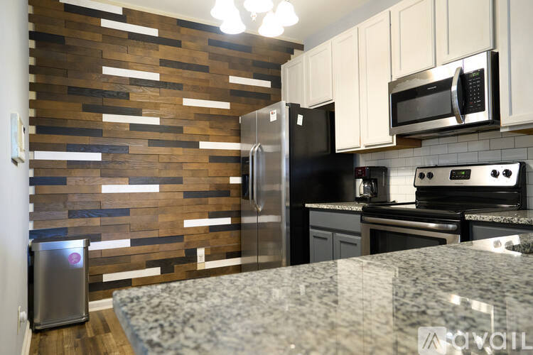 A kitchen with a granite counter top and a wooden backsplash.