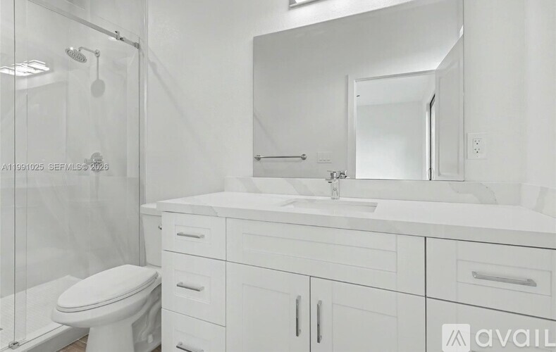 A white bathroom with a toilet, sink, and mirror.