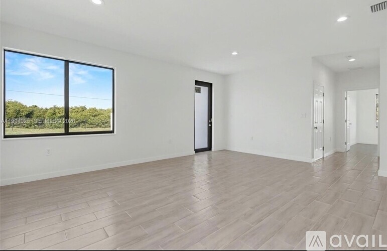 A spacious room with a view of trees through a large window.