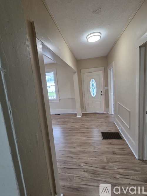 A hallway with a door at the end and a window on the wall.
