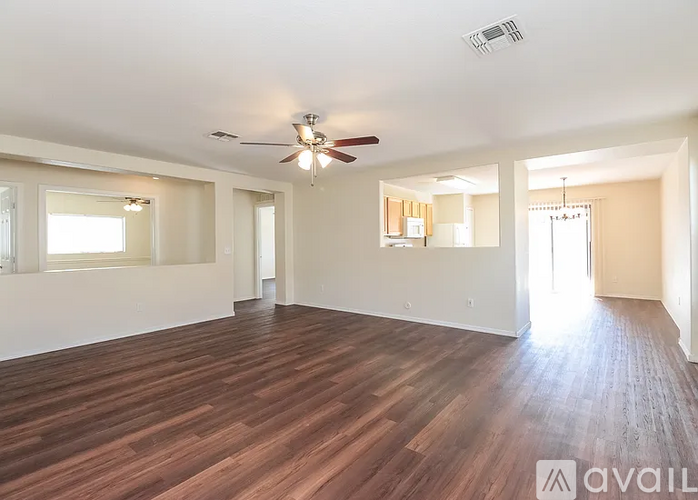 A spacious room with wooden flooring and a ceiling fan.