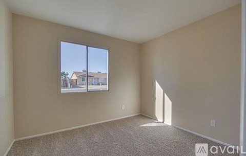 A room with a carpeted floor and a window showing a view of a building outside.