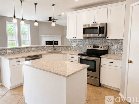 A kitchen with white cabinets and a granite countertop.