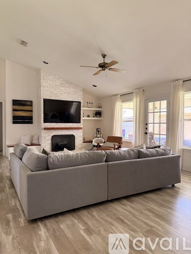 A living room with a grey couch and a fireplace.