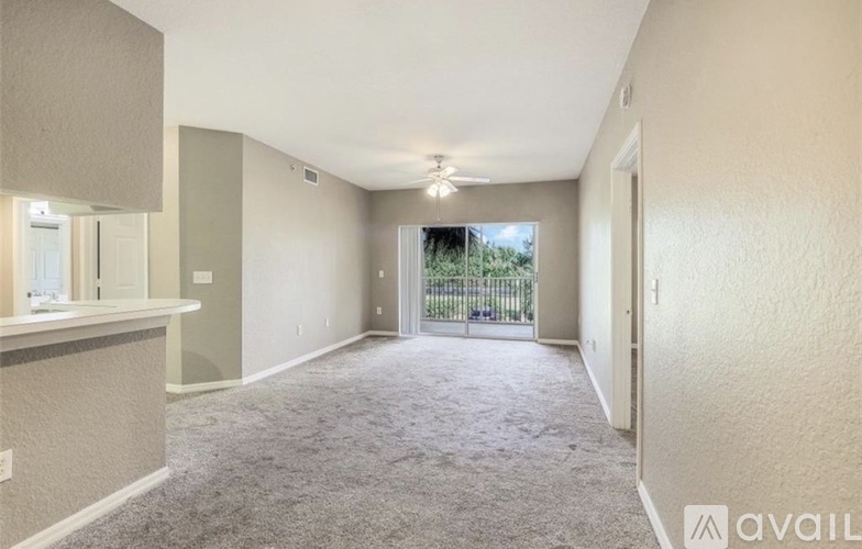 A spacious room with a carpeted floor and a sliding glass door leading to a balcony.