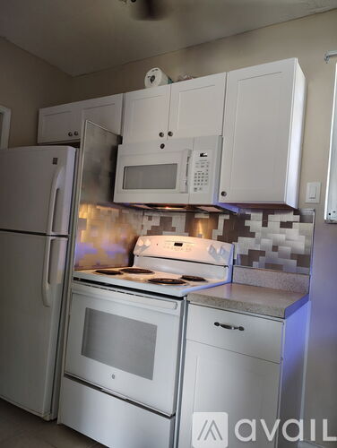A kitchen with white appliances and cabinets.