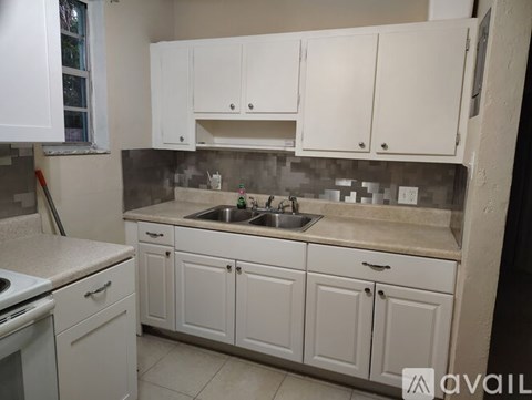 A kitchen with white cabinets and a sink.