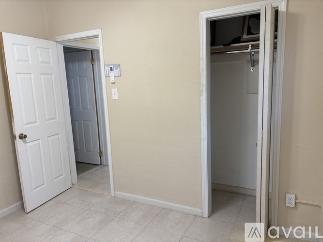 A room with a white door and a white wall with a light switch.