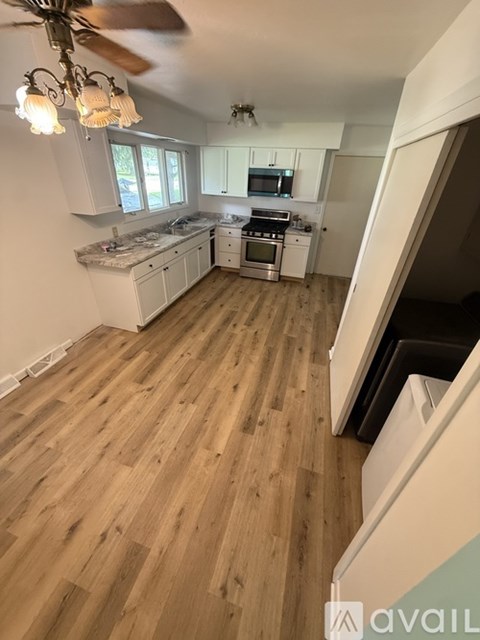 A kitchen with wooden floors and a ceiling fan.