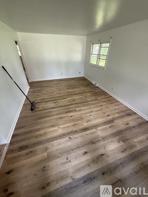 A room with wooden flooring and a window.