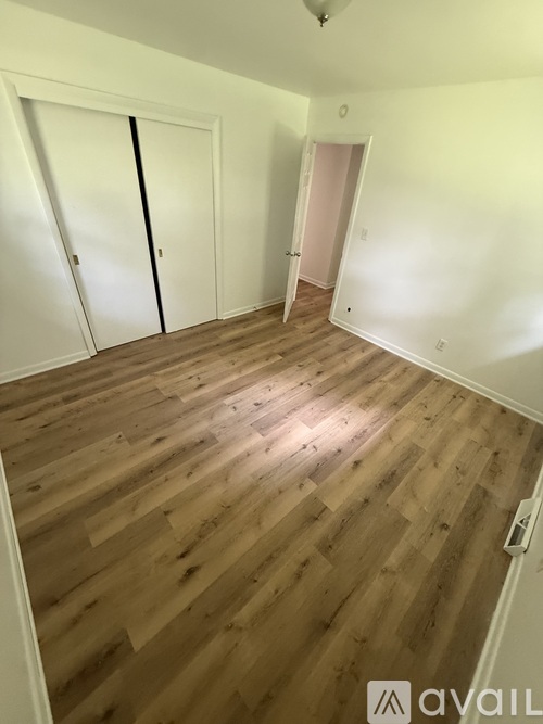 A room with wooden flooring and two doors.