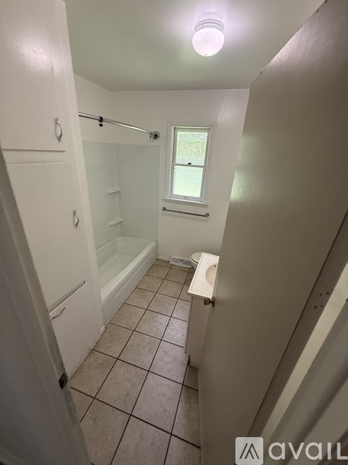 A bathroom with a toilet, tub, and window.
