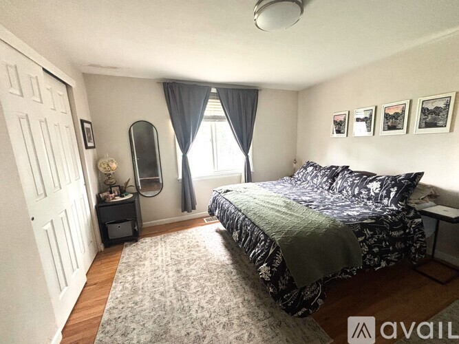 A bedroom with a bed, nightstand, and window with curtains.