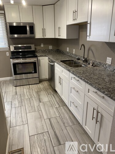 A kitchen with white cabinets and a granite countertop.