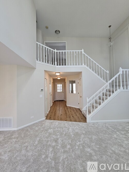 A spacious, empty room with a staircase leading to the upper floor.
