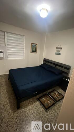 A bedroom with a bed, nightstand, and a painting on the wall.