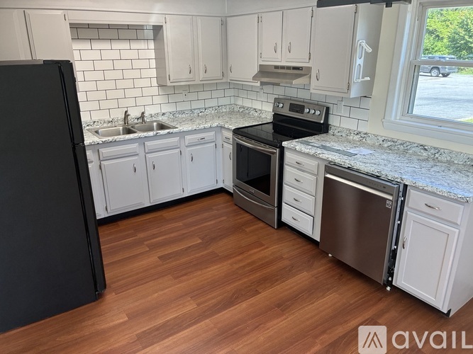 A kitchen with white cabinets and a black refrigerator.
