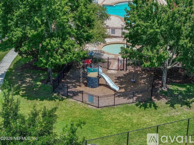 A playground with a slide and a pool in the background.