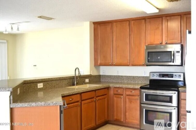 A kitchen with brown cabinets and a granite counter.