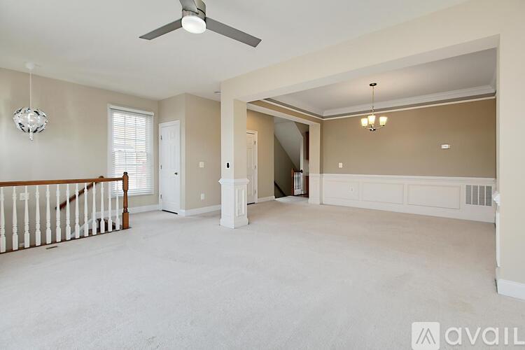 A spacious living room with a ceiling fan and a staircase.