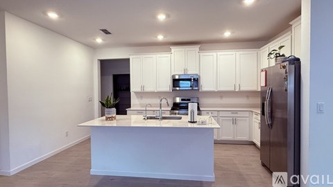 A kitchen with white cabinets and a refrigerator.