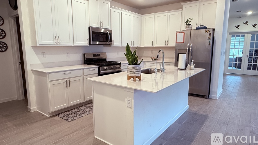 A kitchen with white cabinets and a marble countertop.