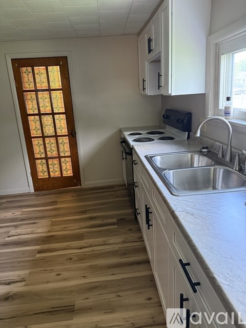 A kitchen with wooden floors and a stove top oven.