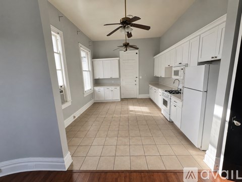 A kitchen with white cabinets and a ceiling fan.