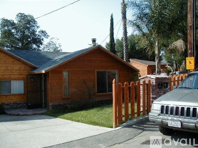 A house with a wooden fence and a car parked in front.