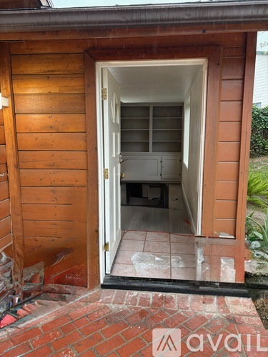A wooden structure with a doorway leading to a room with a window.