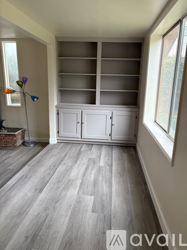 A room with a grey floor and a white cabinet with glass doors.