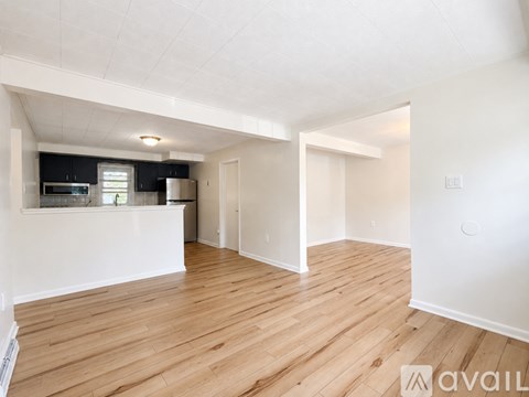 A spacious room with wooden flooring and white walls.