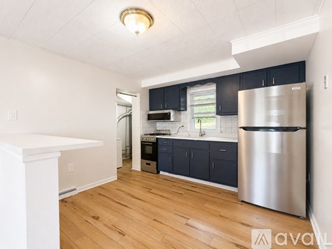 A kitchen with a stainless steel refrigerator and wooden floors.