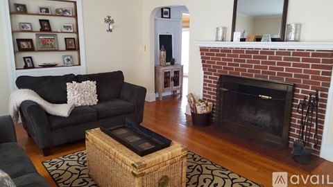 A living room with a black couch and a fireplace.
