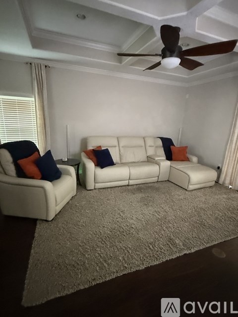 A living room with a white couch and a ceiling fan.