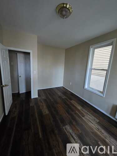 A room with wooden floors and a window with blinds.