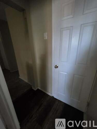 A hallway with a white door and a light switch on the wall.