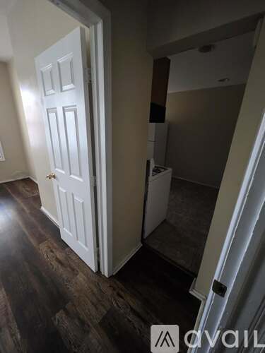 A white door is open to a room with a wood floor.