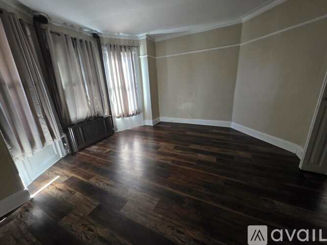 A room with wooden flooring and a window with curtains.