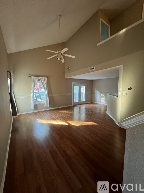 A spacious room with wooden floors and a ceiling fan.