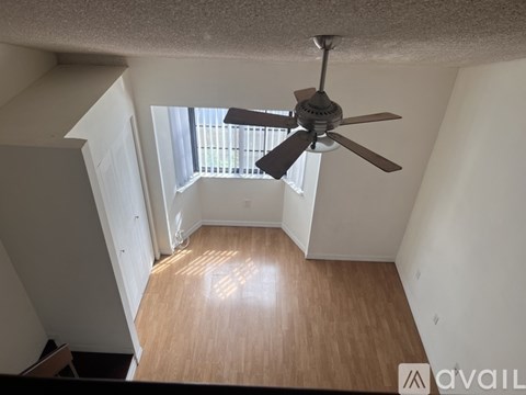 A room with a ceiling fan and wooden flooring.