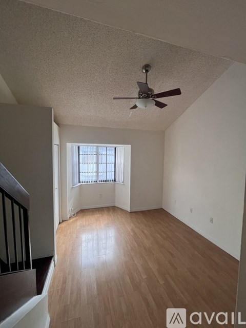 A room with a ceiling fan and wooden flooring.
