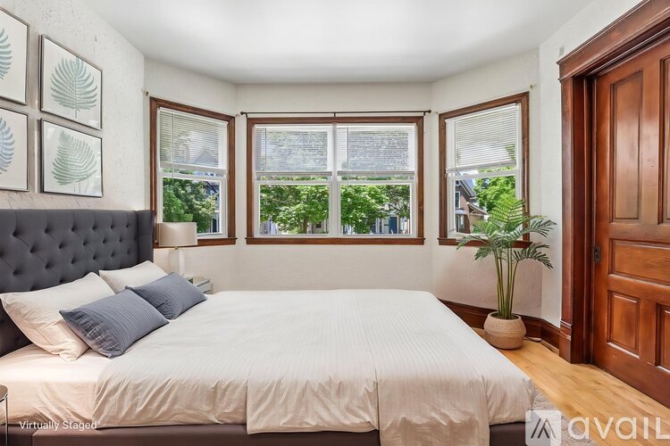 A bedroom with a large bed and a window overlooking a garden.