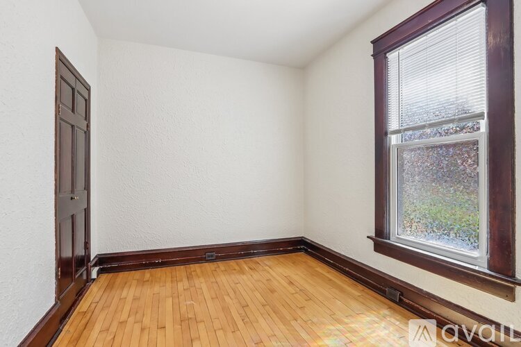 A room with a wooden floor and a window with a view of trees outside.